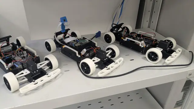 Three small white 3D-printed race cars on a shelf.