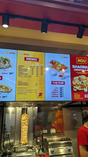 A shawarma counter with a yellow and red menu board.
