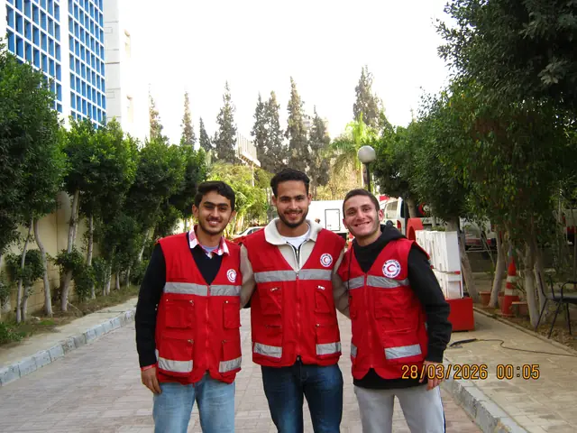 Three volunteers in red vests outside the building.