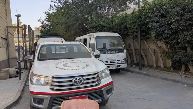 A Red Crescent pickup and minibus parked in the yard.
